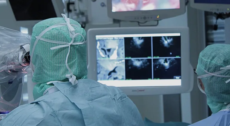 En person iført kirurgiske scrubs og en maske ser på en dataskjerm