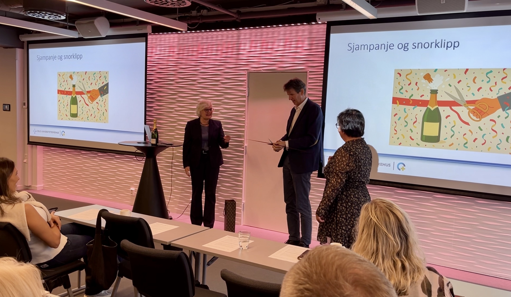 En mann og kvinne som står foran en skjerm med en presentasjon