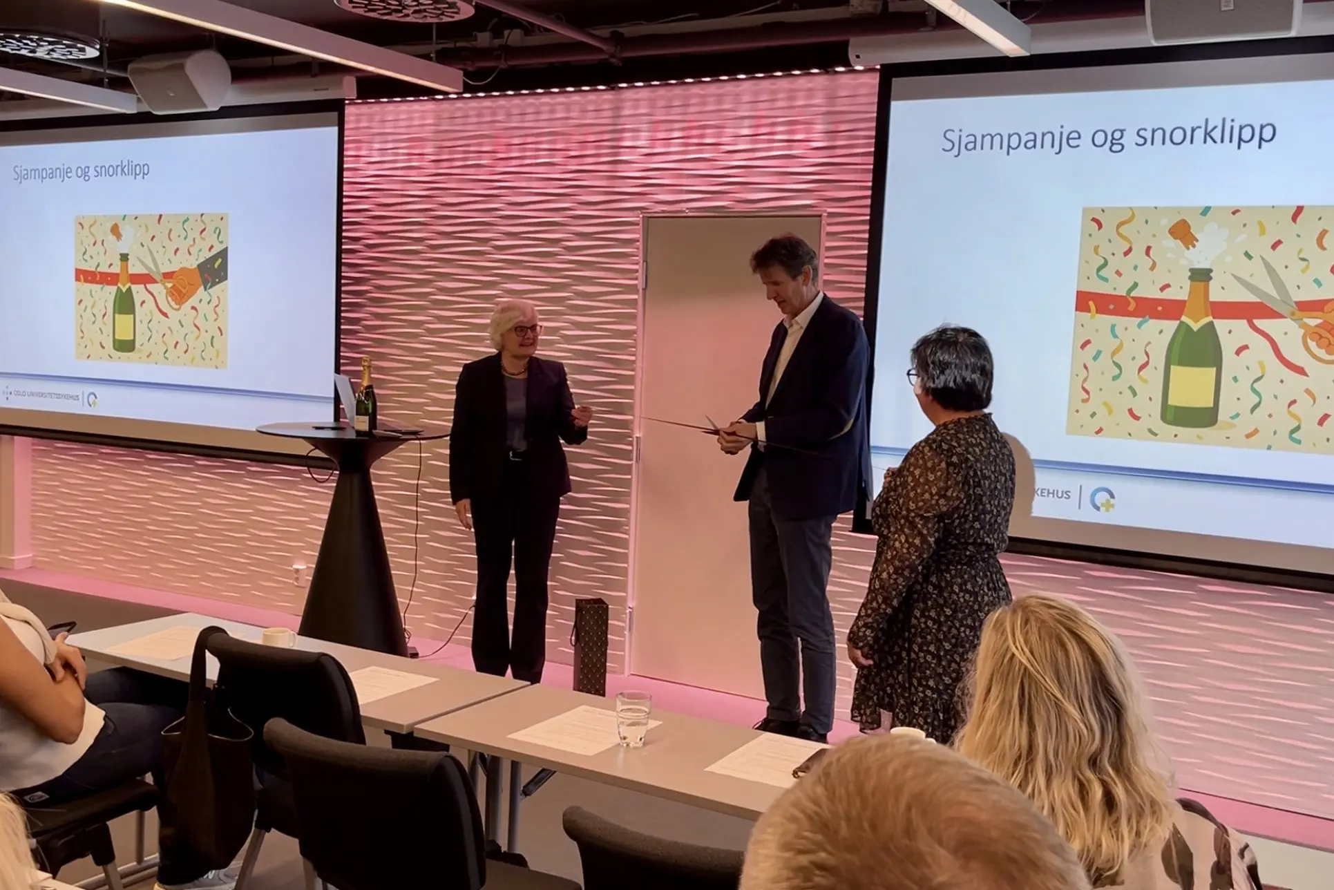 En mann og kvinne som står foran en skjerm med en presentasjon