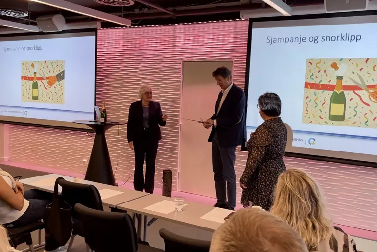 En mann og kvinne som står foran en skjerm med en presentasjon